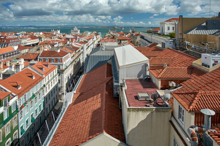 High angle view over the terracotta rooftops of the Baixa district toward the Tagus River and Praca...