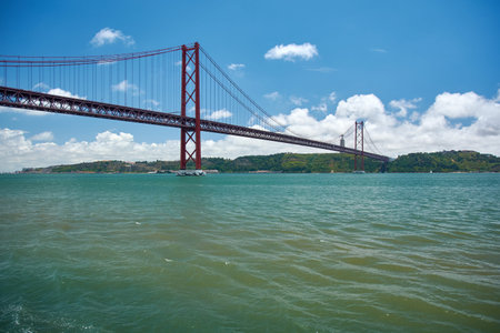 Wide shot of the 25 de Abril Bridge crossing the Tagus River toward Almada, Lisbon, Portugal,...