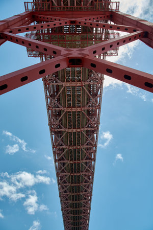 Low angle perspective looking up at the steel structure and underside of the 25 de Abril Bridge,...