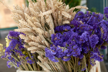 Close up of a mixed bouquet containing purple Statice Limonium sinuatum and dried wheat stalks at a...