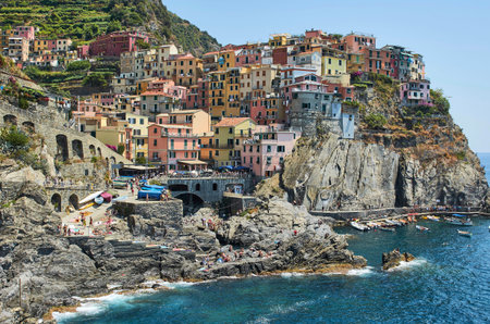 Colorful historic houses built on the cliffs of Manarola village overlooking the sea, Cinque Terre,...