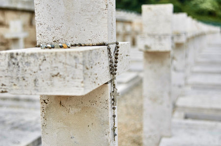 Close up of a rosary hanging from a stone cross marking a soldier's grave at the Polish War...