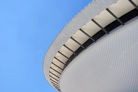 Low angle architectural detail of the Spodek Arena roof and facade against a blue sky, Katowice,...