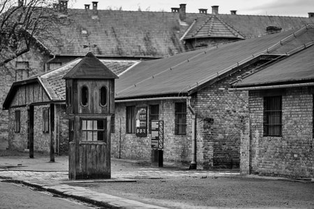 Wooden guard post and brick buildings with trees in Oswiecim