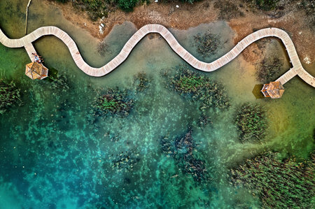 Top down view of visitors sitting on a wooden pier next to a gazebo over turquoise quarry water at...