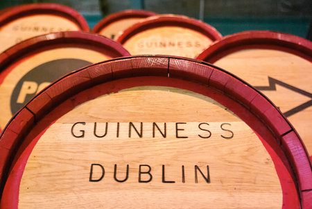 High angle close up of several wooden Guinness beer barrels stacked together showing the painted...