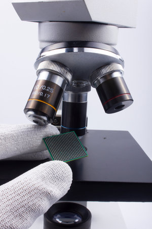 Semiconductor BGA chip in fingers and optical microscope - IC inspection.の写真素材