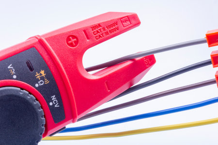 The electrician measures the current in the phase wire with a meter on a gray backgroundの写真素材