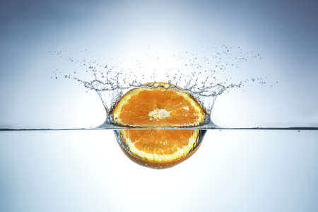 Fresh orange drops in water