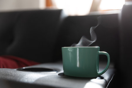 Cup of hot drink on sofa in living room, closeup with smokeの写真素材