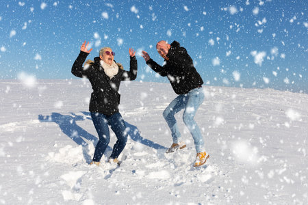 Couple having fun on snow in winter. Man and woman playing with snow.の写真素材