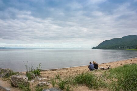 couple sitting on the beach at the lakeの写真素材