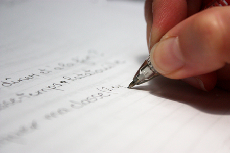 hand with a pencil writing on a piece of paper