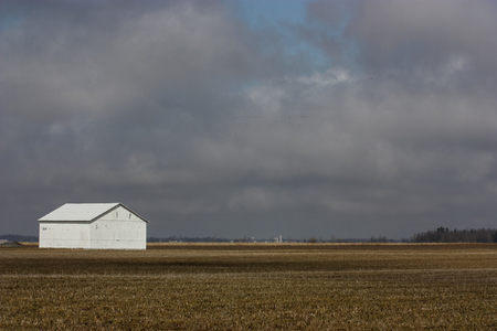 white barn in a field on a cloudy dayの写真素材