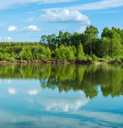 Beautiful lake landscape with sky and trees reflected in the waterの写真素材