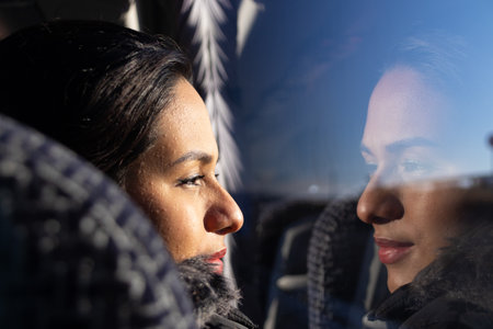 Colombian woman traveling by bus, looking out the window, smiling and her face reflected in the...