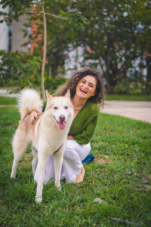 happy woman next to a white dog in a parkの写真素材