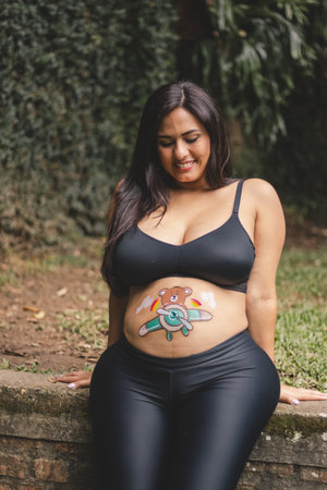 pregnant latina woman looking at her bellyの写真素材