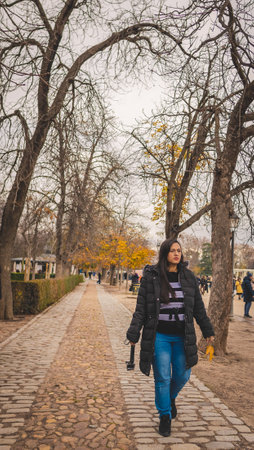 Latin woman walking in Madrid's El Retiro park in autumn.の写真素材