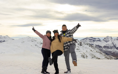 Three latin adults, happy and smiling, jumping in the snow of the Pyreneesの写真素材