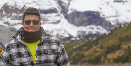 Young man on vacation in europe and mountains with snow behind himの写真素材
