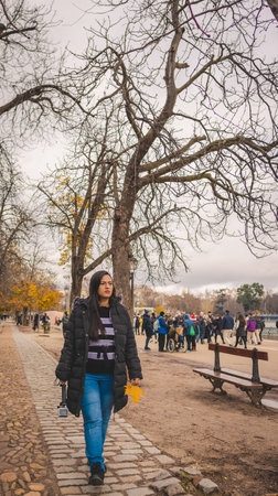 Young latin woman walking in Madrid's El Retiro park in autumn.の写真素材