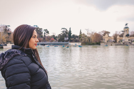 Young latin woman looking at the horizon at the lake in El Retiro Park in Madrid, Spain.の写真素材