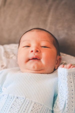 newborn baby smiling, lying down, right hand raisedの写真素材