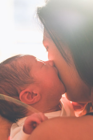 Newborn baby kissing his mother on her face
