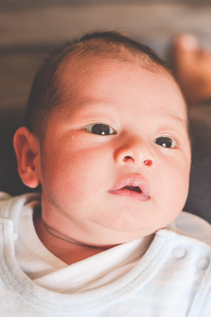 Face of newborn baby with open eyes, white skin and black hairの写真素材