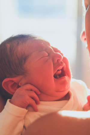 Newborn baby crying in mother's armsの写真素材