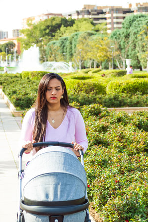 Woman walking in a park with gray strollerの写真素材