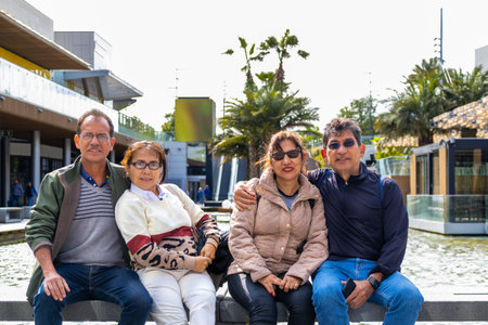 Two latin married couples in the outdoor area of a shopping mall, smiling and looking at the camera.の写真素材