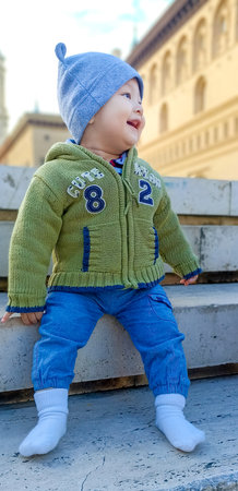 Beautiful baby sitting on a city stairwell in winterの写真素材