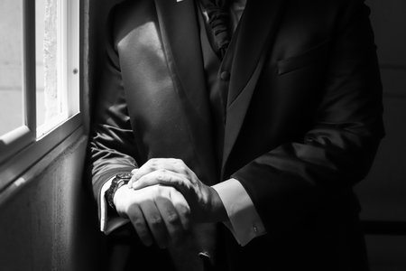 Torso of man next to a window with his hands claspedの写真素材