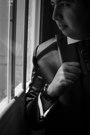 Man by a window and his right arm up showing his watchの写真素材