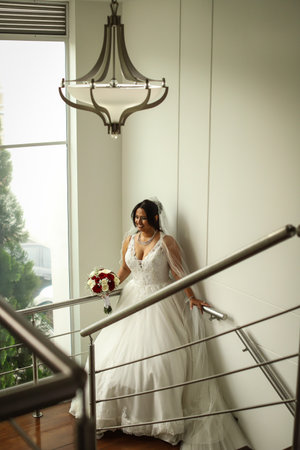 Beautiful latin woman wearing her white wedding dress and a bouquet of rosesの写真素材