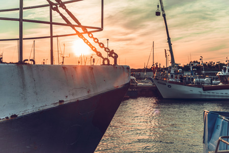 Sail Boats and motor boats moored in the harbor and dock with amazing view and nice sunset. Near sea and parts of fishing boats. Cruise and sea expeditions.の写真素材