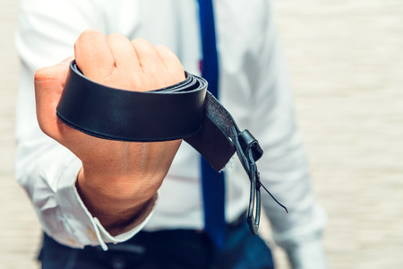 Man holds in hand belt. Businessman is angry and shows his angles in front of the camera.の写真素材