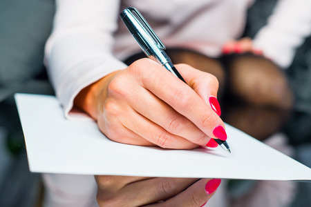 Woman writes something on paper, starts to write a letter. Person sign document, write on paper using pen.の写真素材