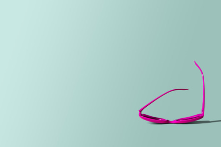 Pink sunglasses on a pastel background. Pink sunglasses lie sideways on a blue, turquoise background. Pastel background. The concept of holidays, departure in the summer, rest. Travel agency.の写真素材