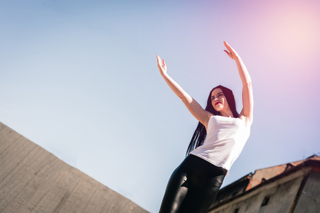 Attractive spontaneous woman exercising outdoors. Authenticity and Spontaneity. The girl is performing an authentic warm-up. The girl does physical exercises, care for her figure. Playing sports.の写真素材