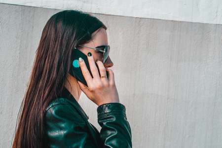 Attractive spontaneous woman talking on the phone. Authenticity and Spontaneity. Authentic conversation over the phone. The girl in sunglasses holds a mobile phone in hand.の写真素材