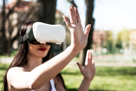 A woman with VR glasses is playing outside. A young and smiling girl is wearing virtual reality...