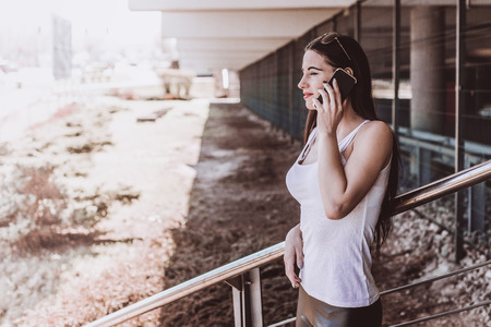 Woman talking on the phone. Authenticity and Spontaneity. Authentic conversation over the phone. The girl in sunglasses holds a mobile phone in hand.の写真素材