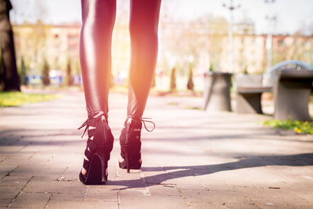 Legs view of a woman walking with flowers. The girl in black pants moves around park outside. Beuty and fashion concept.の写真素材