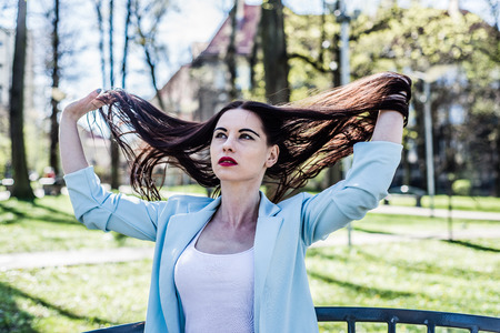 A nostalgic portrait of women sitting on a bench and scattering hair in the wind. A thoughtful and serious woman looks ahead.の写真素材