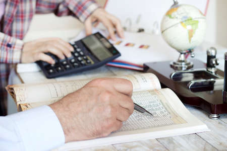Businessman Analyzing and using graphic calculator, world map in the officeの写真素材