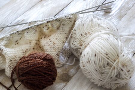 Skeins of wool and knitting needles on wooden background