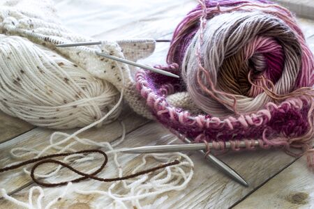 Skeins of wool and knitting needles on wooden background